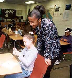 photo of student helping another student, who is knitting